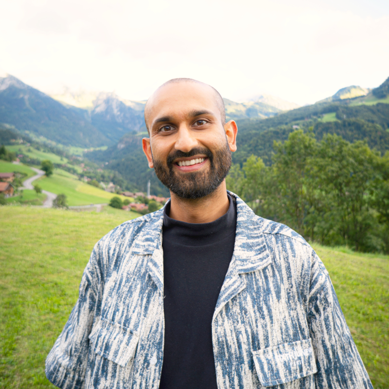 A self-portrait photograph of Ian Ahuja with mountainous backdrop.