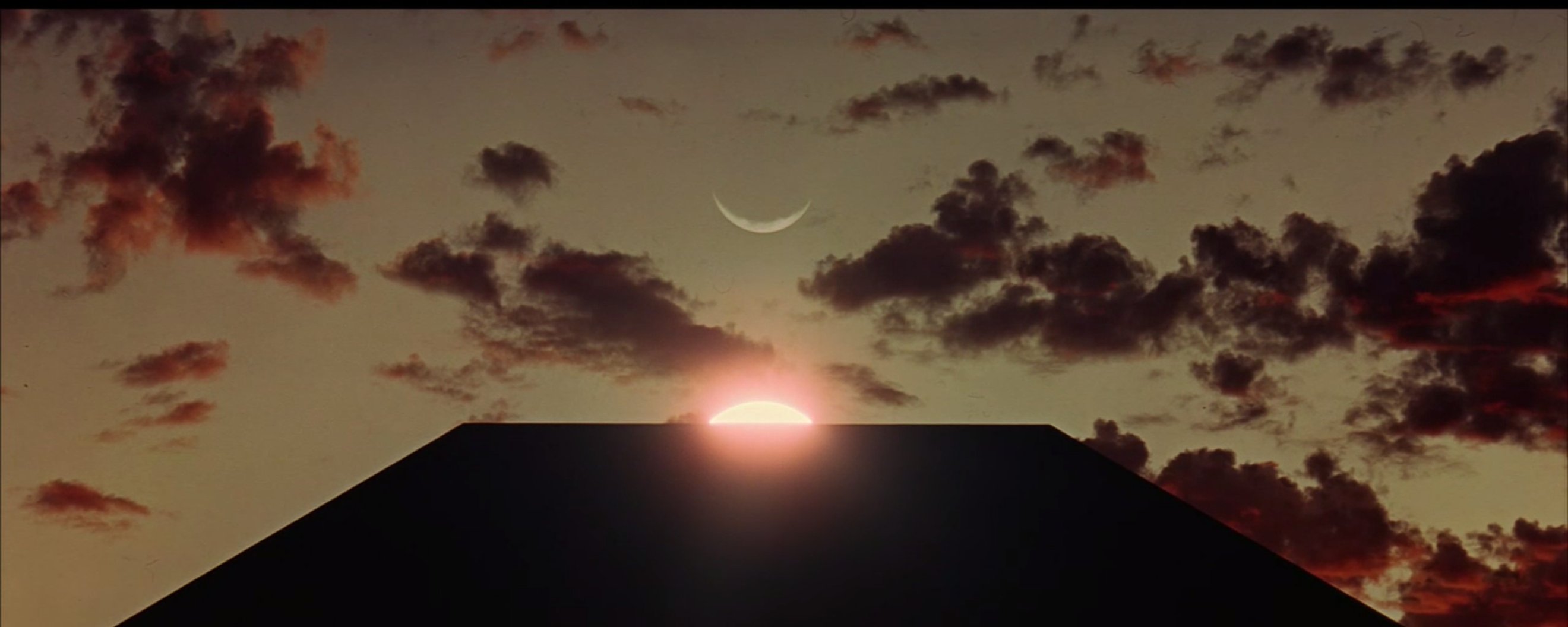 pyramid against a crescent moon and setting sun